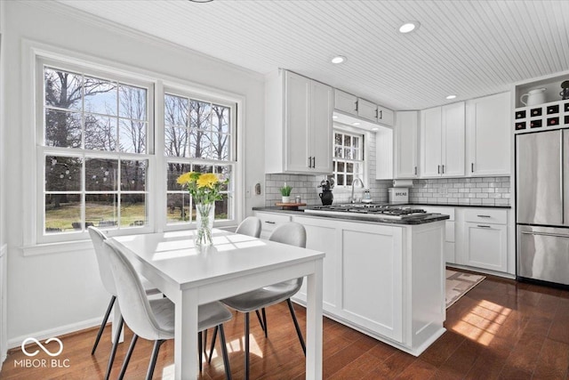 kitchen featuring backsplash, dark wood-type flooring, dark countertops, and appliances with stainless steel finishes