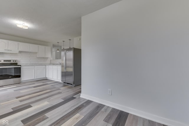 kitchen with baseboards, light countertops, white cabinets, appliances with stainless steel finishes, and backsplash