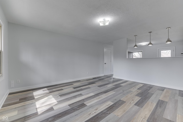 unfurnished room with wood finished floors, baseboards, and a textured ceiling