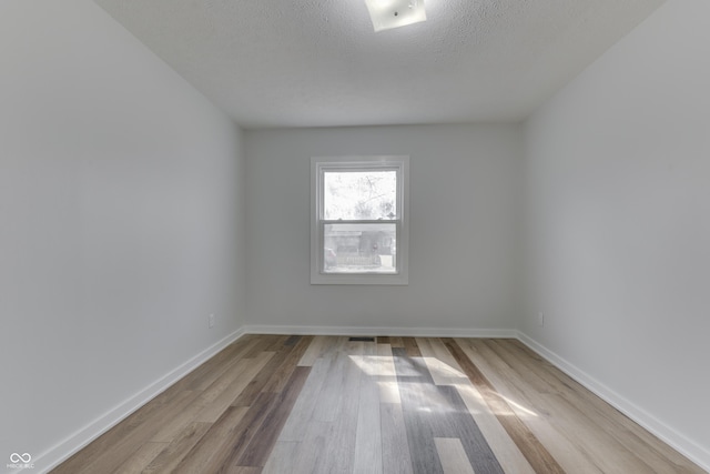 empty room featuring baseboards, a textured ceiling, and wood finished floors