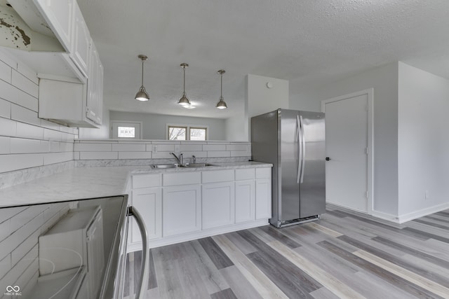 kitchen with freestanding refrigerator, a sink, white cabinets, range, and light wood-type flooring