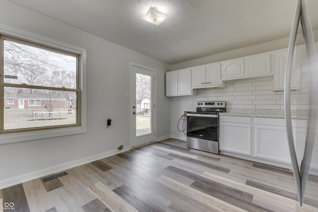 kitchen featuring visible vents, backsplash, light wood-type flooring, stainless steel electric range, and white cabinetry