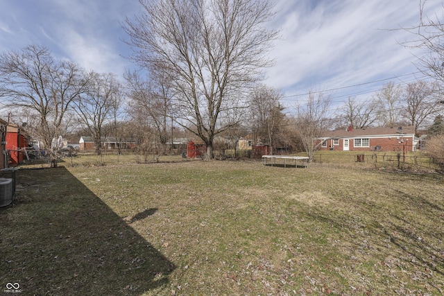 view of yard featuring central AC unit, a trampoline, and fence