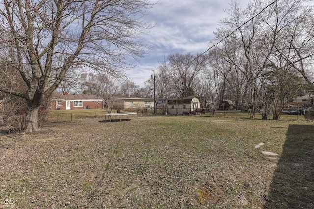 view of yard featuring a trampoline and fence