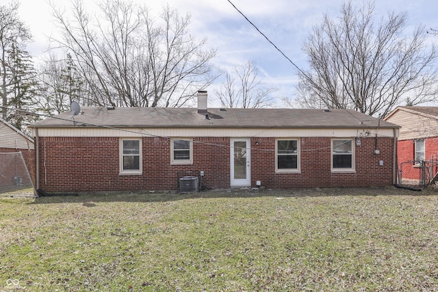 rear view of house with a yard, brick siding, and central AC