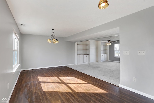 interior space with built in shelves, wood finished floors, baseboards, visible vents, and ceiling fan with notable chandelier