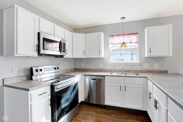 kitchen featuring a sink, a textured ceiling, white cabinetry, appliances with stainless steel finishes, and dark wood-style flooring