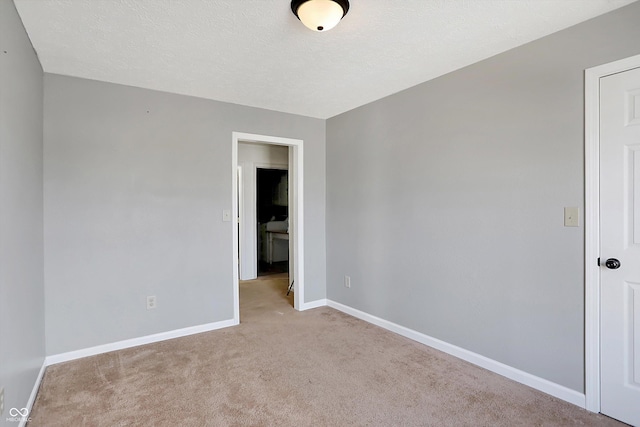 carpeted empty room with baseboards and a textured ceiling