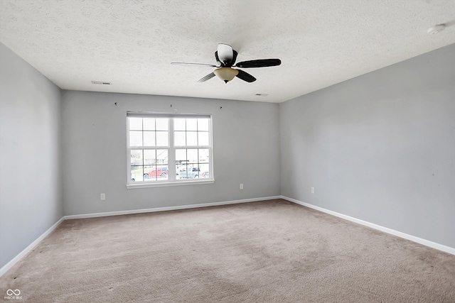 spare room featuring baseboards, visible vents, carpet floors, ceiling fan, and a textured ceiling