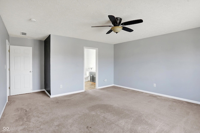 unfurnished bedroom with visible vents, a textured ceiling, connected bathroom, carpet flooring, and baseboards