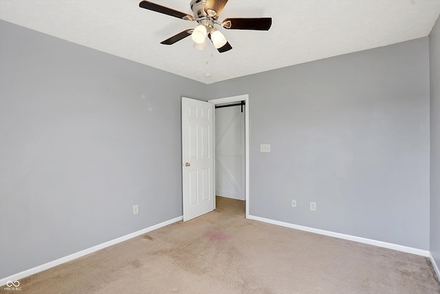 carpeted empty room with a ceiling fan and baseboards