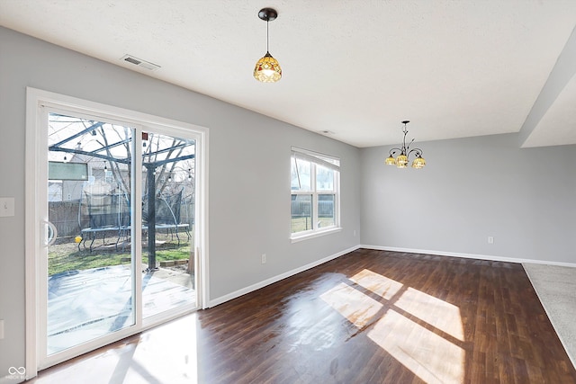 unfurnished dining area with baseboards, visible vents, dark wood-style flooring, a sunroom, and a chandelier