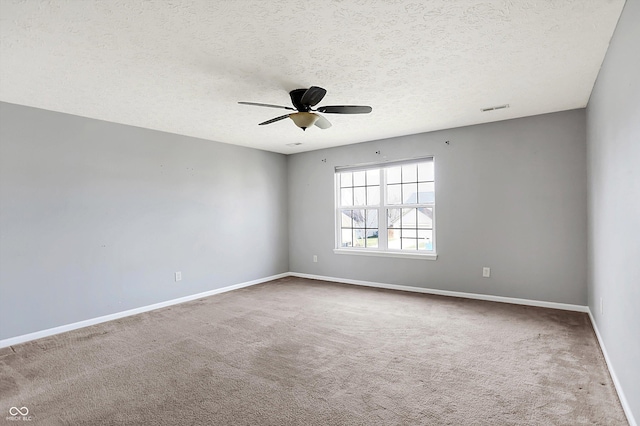 carpeted empty room featuring visible vents, a textured ceiling, baseboards, and ceiling fan