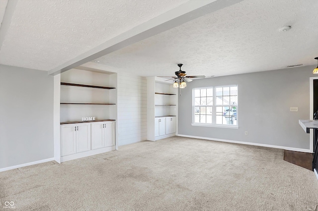 unfurnished living room featuring a ceiling fan, carpet, and a textured ceiling