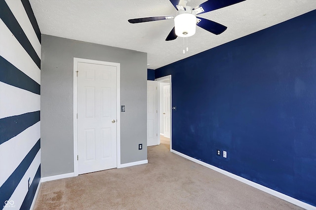 unfurnished bedroom with baseboards, ceiling fan, a textured ceiling, and carpet