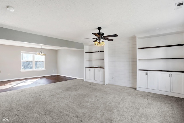 unfurnished living room featuring ceiling fan with notable chandelier, carpet, visible vents, and a textured ceiling