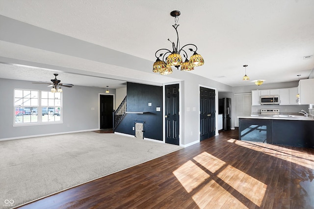 unfurnished living room with baseboards, stairs, dark wood-type flooring, and a sink