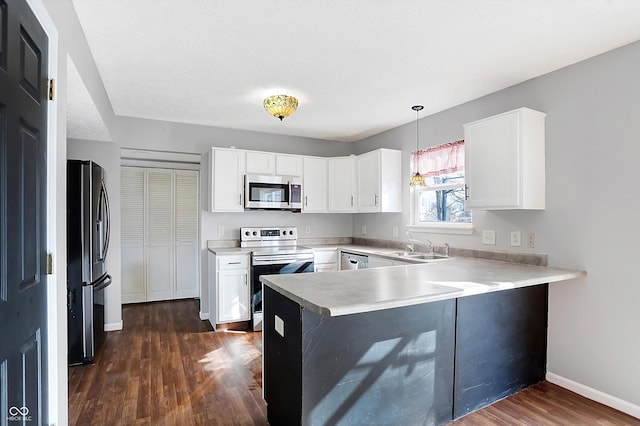 kitchen featuring a peninsula, dark wood-style flooring, light countertops, appliances with stainless steel finishes, and white cabinetry