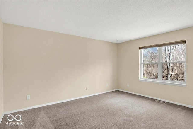 unfurnished room with visible vents, baseboards, carpet, and a textured ceiling