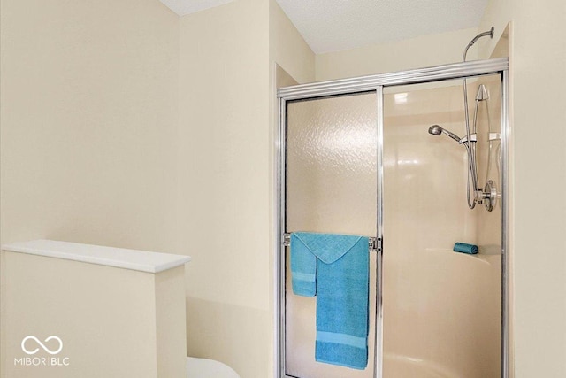 full bathroom featuring toilet, a stall shower, and a textured ceiling