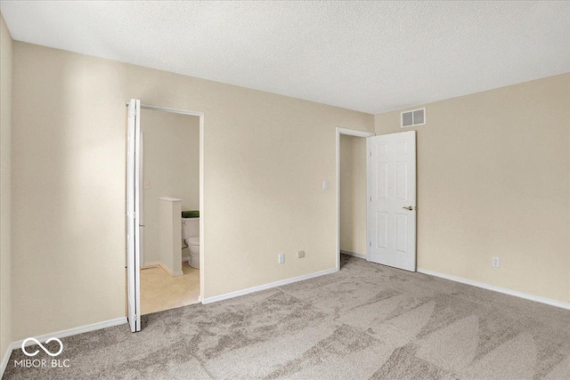 unfurnished bedroom featuring baseboards, visible vents, a textured ceiling, and carpet