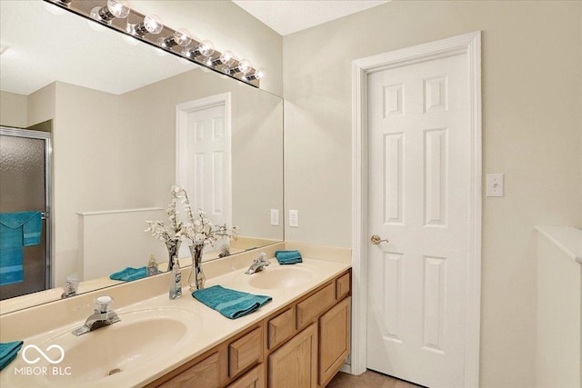 bathroom with double vanity, a shower stall, and a sink