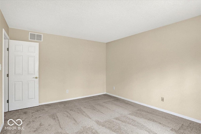 carpeted spare room featuring visible vents, a textured ceiling, and baseboards