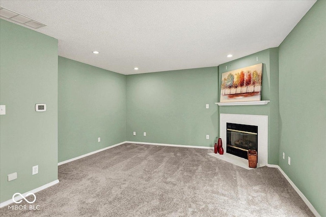 unfurnished living room with a fireplace with flush hearth, a textured ceiling, baseboards, and visible vents