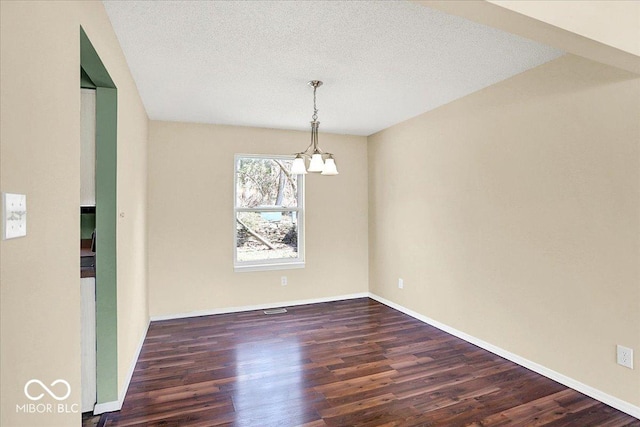 unfurnished dining area featuring a textured ceiling, wood finished floors, baseboards, and a chandelier