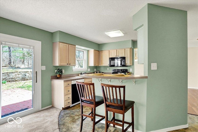 kitchen featuring a kitchen bar, range with electric cooktop, light brown cabinets, black microwave, and dishwasher