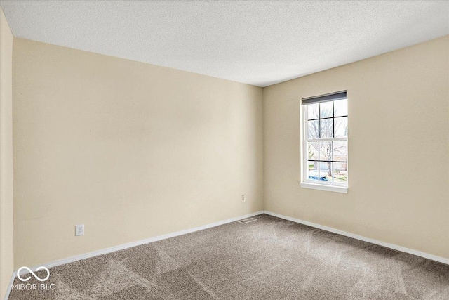 carpeted spare room with baseboards and a textured ceiling