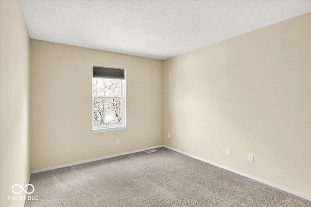 carpeted spare room with visible vents, baseboards, and a textured ceiling