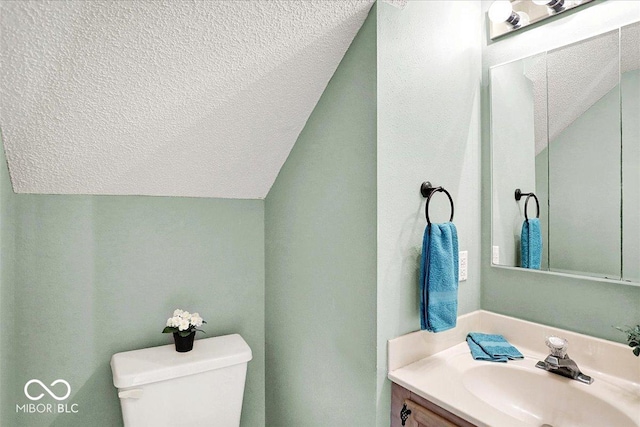 bathroom with lofted ceiling, toilet, vanity, and a textured ceiling