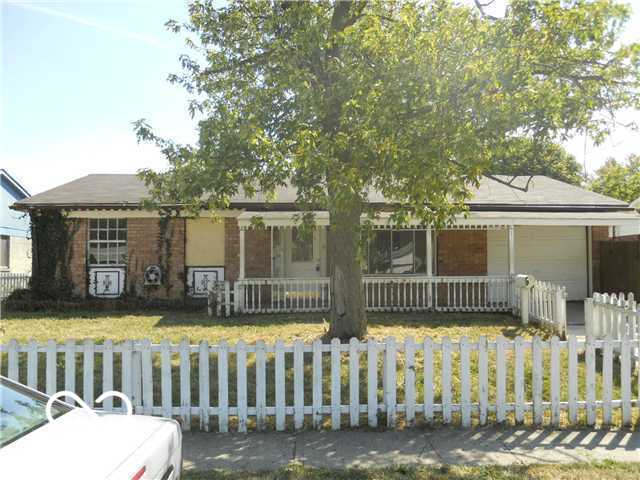 view of front of home with brick siding, a fenced front yard, a porch, a front yard, and a garage