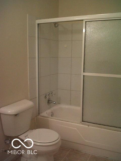 bathroom with tile patterned floors, toilet, and shower / bath combination with glass door