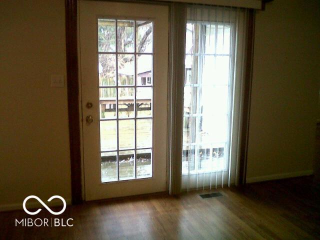 doorway to outside with plenty of natural light, wood finished floors, and visible vents