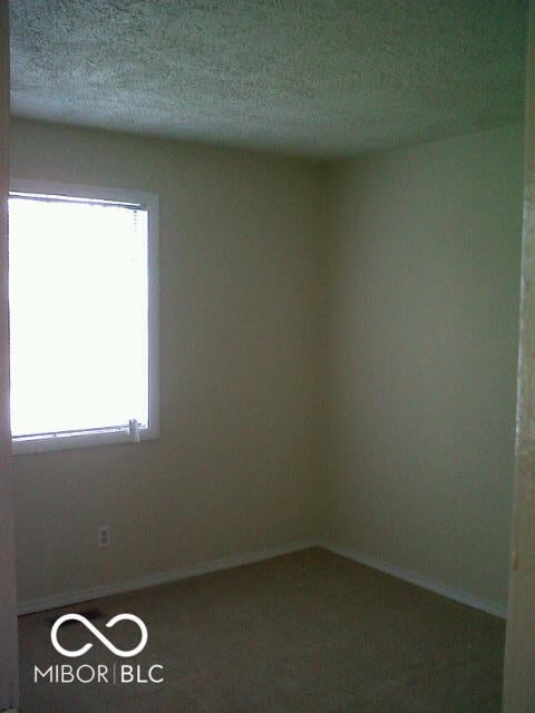 empty room featuring a textured ceiling and baseboards