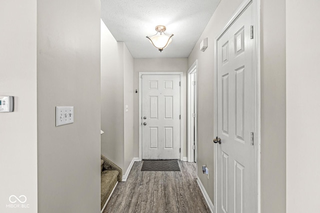 doorway to outside featuring a textured ceiling, stairs, baseboards, and wood finished floors