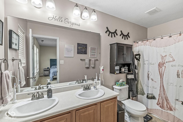 ensuite bathroom featuring double vanity, toilet, visible vents, and a sink