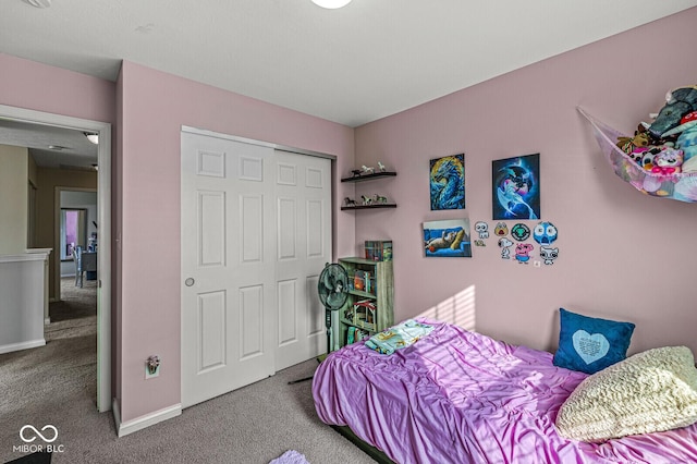 carpeted bedroom featuring a closet and baseboards