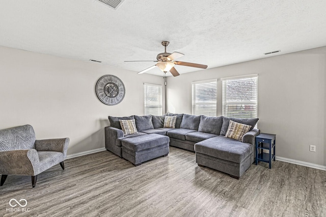 living area featuring baseboards, wood finished floors, visible vents, and ceiling fan