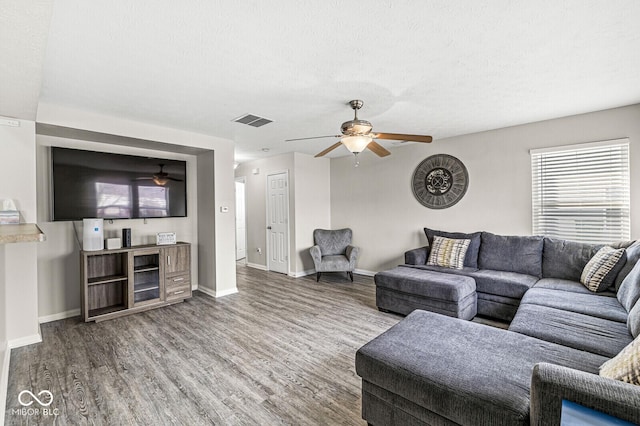 living area with visible vents, baseboards, a ceiling fan, and wood finished floors