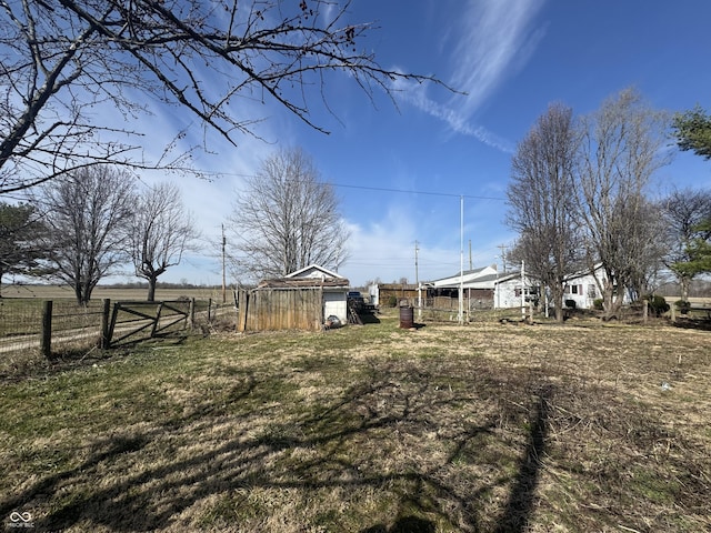 view of yard featuring an outbuilding, a storage unit, and fence