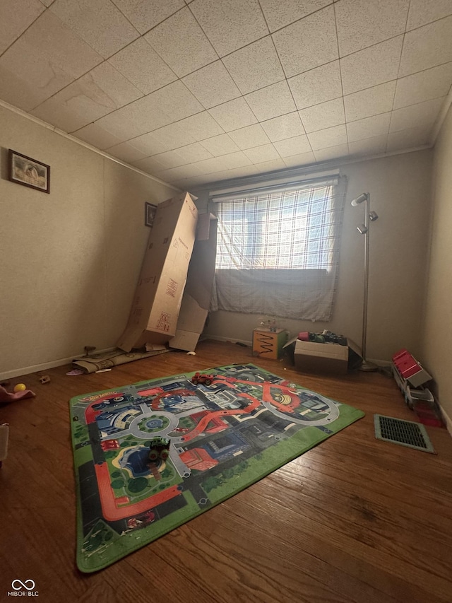 interior space featuring crown molding, wood finished floors, visible vents, and baseboards