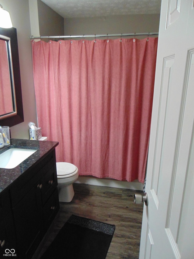 full bath featuring curtained shower, toilet, wood finished floors, a textured ceiling, and vanity