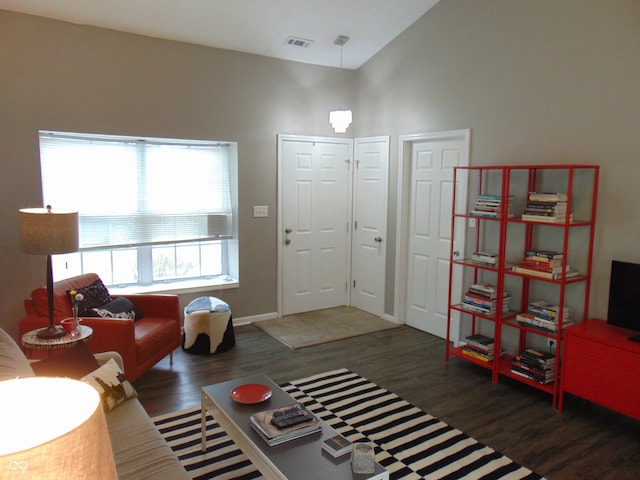 living area featuring visible vents, high vaulted ceiling, and wood finished floors