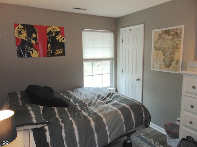 bedroom with visible vents, baseboards, and wood finished floors