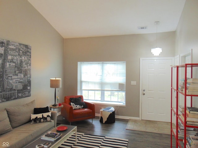 living room featuring vaulted ceiling, wood finished floors, visible vents, and baseboards