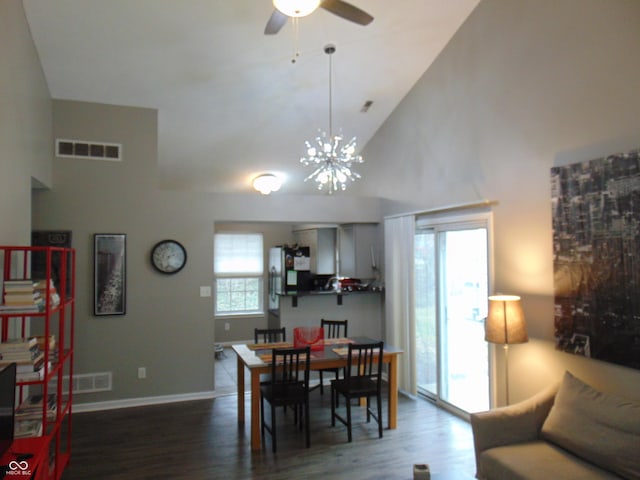 dining area featuring ceiling fan with notable chandelier, wood finished floors, visible vents, and high vaulted ceiling