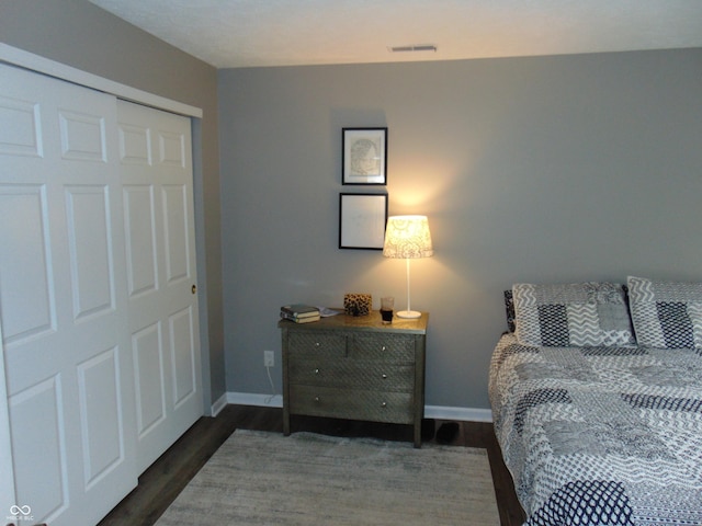 bedroom with a closet, visible vents, baseboards, and wood finished floors